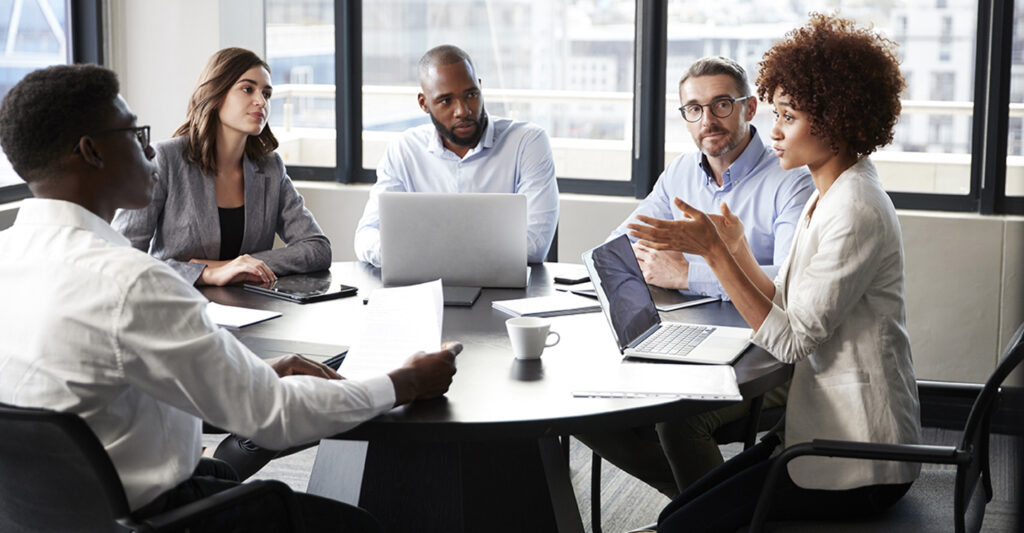 Female consultant leading a strategic clinical supply chain meeting with pharmaceutical professionals in a modern office.