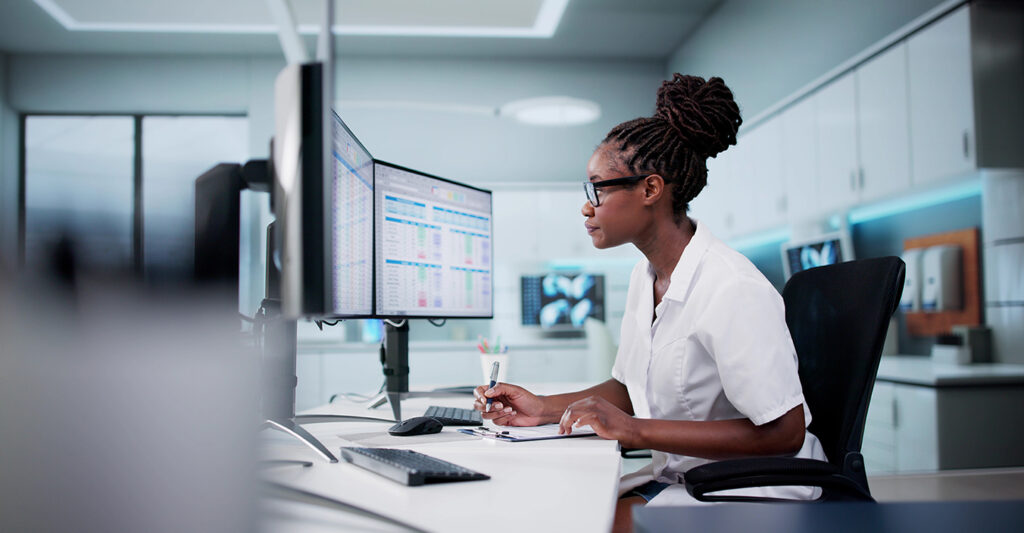 Hospital doctor reviewing billing codes on desktop spreadsheet to support clinical supply chain management