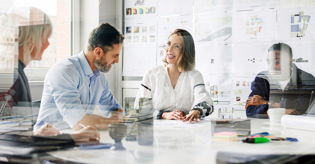 Diverse group of professionals collaborating in a bright modern workspace, representing Clinical Supply Consulting’s third-party script writing services for IRT UAT success.