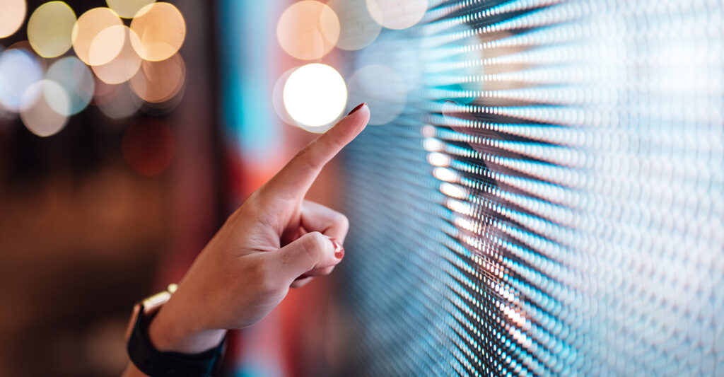 Female hand interacting with illuminated digital interface representing modern clinical trial technology and UAT oversight.